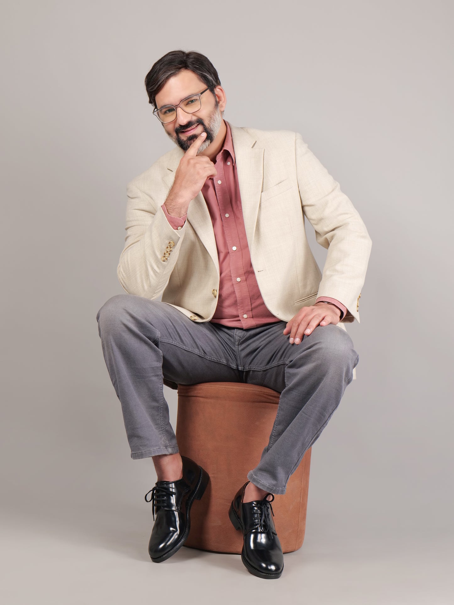 Black Blucher Goodyear welted leather shoes worn by a seated model in a reflective pose