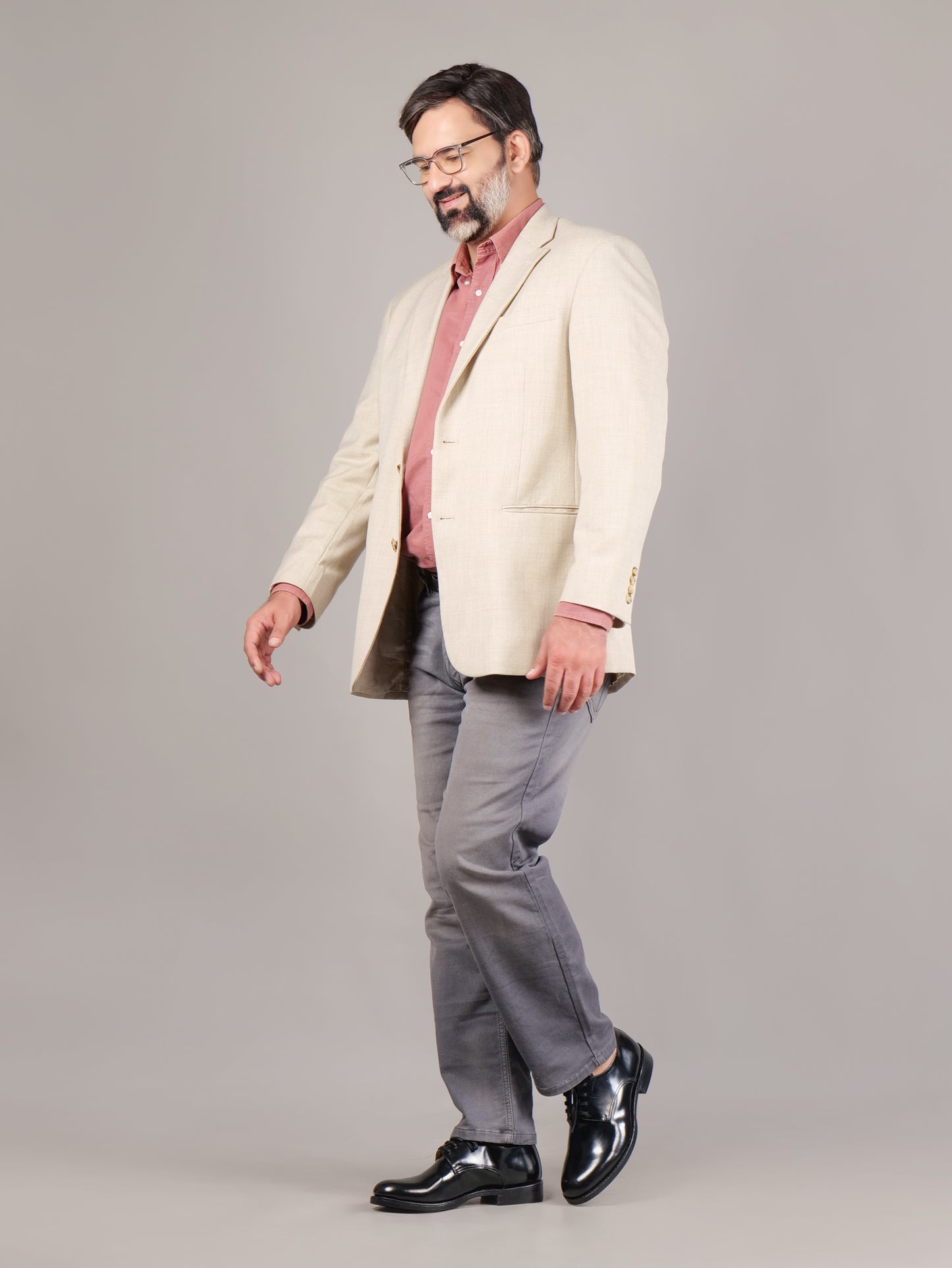 Male model walking in black Blucher Goodyear welted leather shoes against a gray background