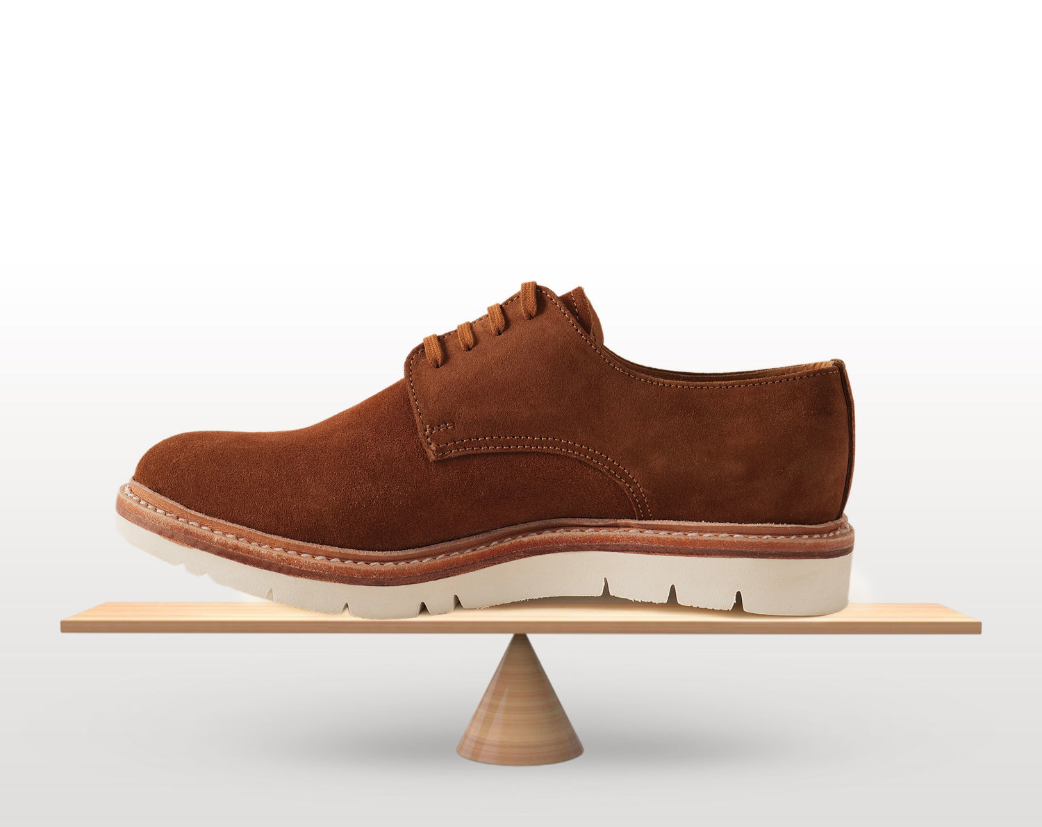 Conceptual image of a Blucher shoe placed on a balance scale to illustrate balanced design