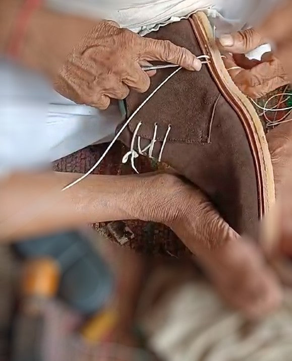 Artisan hand-stitching a leather Blucher shoe in our workshop